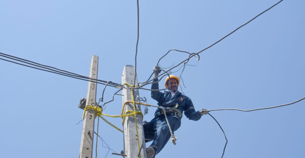 man in black jacket and black pants wearing black helmet on brown electric post during daytime