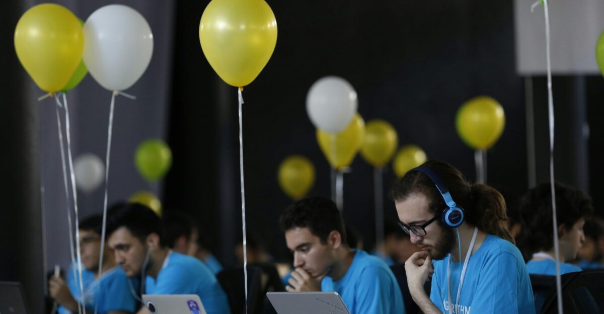 a group of people sitting at a table with laptops