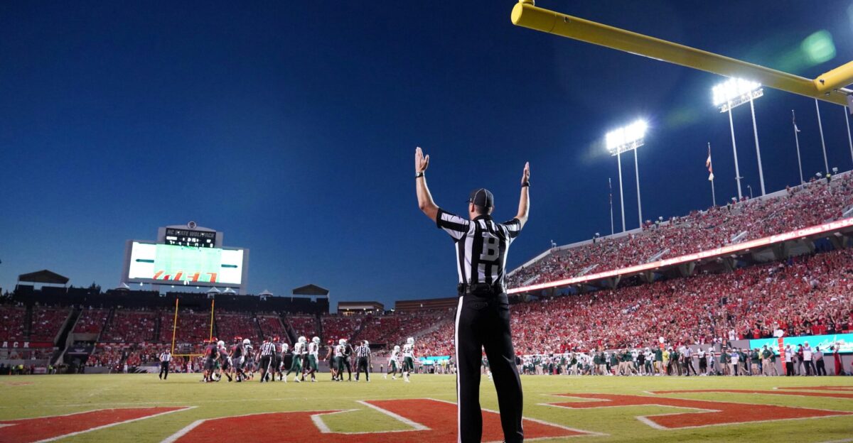a football player standing on a field with his arms in the air