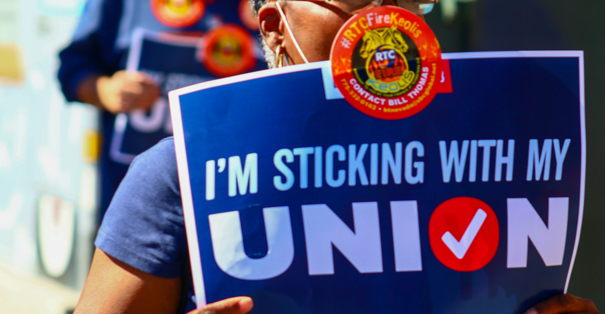 a woman holding a sign that says i m sticking with my union