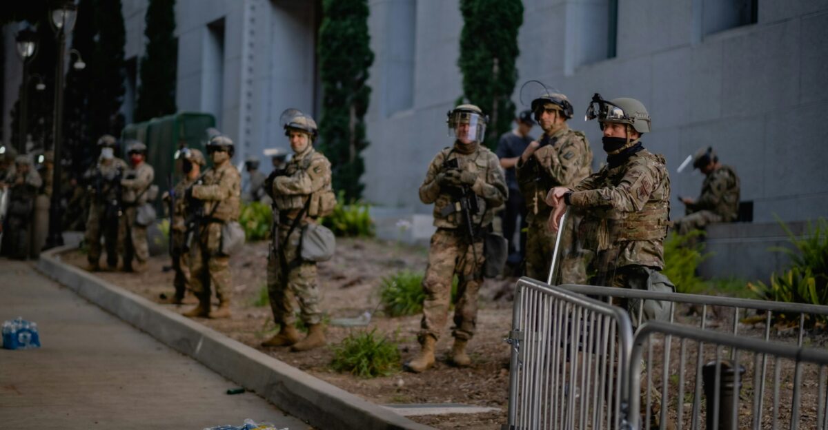 a group of people on a sidewalk near a fence