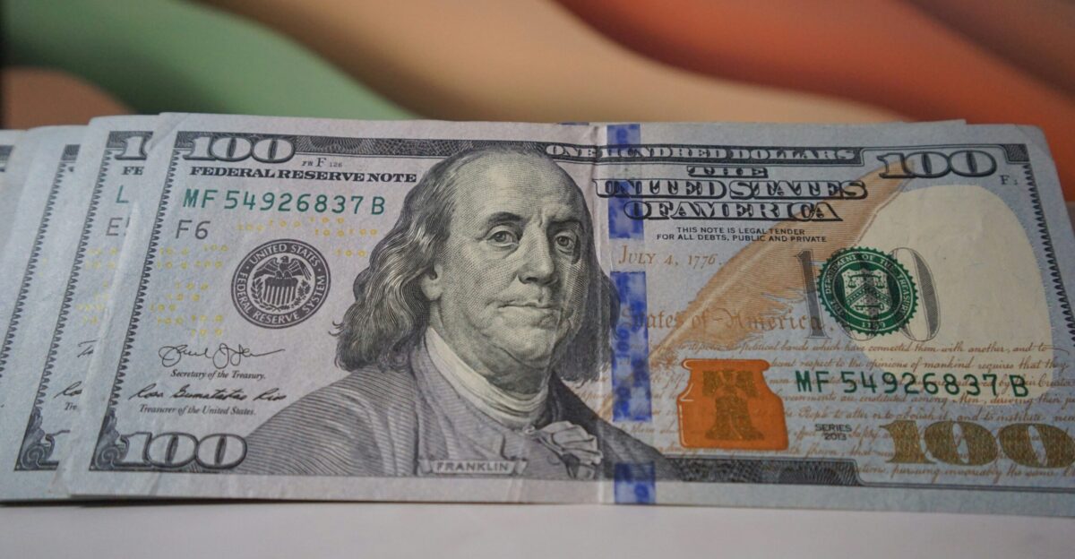 a stack of one hundred dollar bills sitting on top of a table