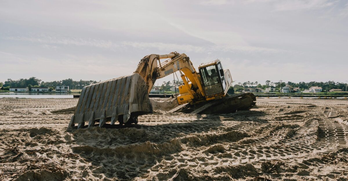 a bulldozer digging in the sand on a beach