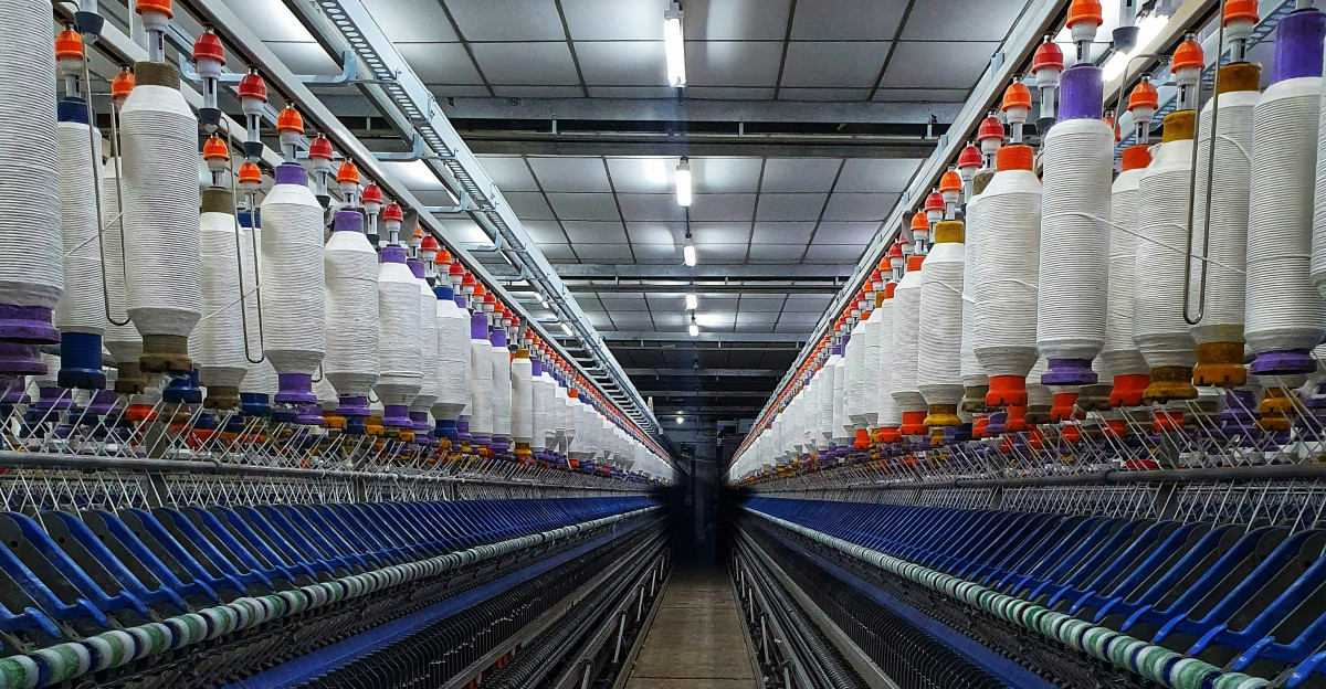a large room with rows of machines and spools of thread