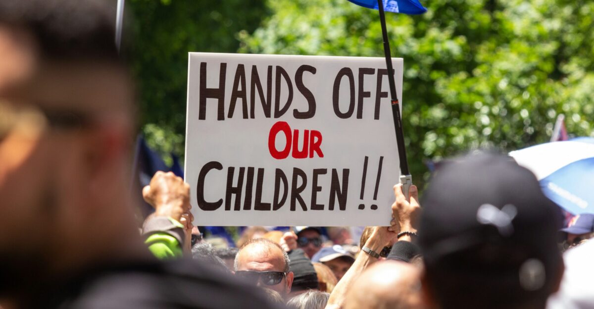 a protest with a sign that reads hands off our children