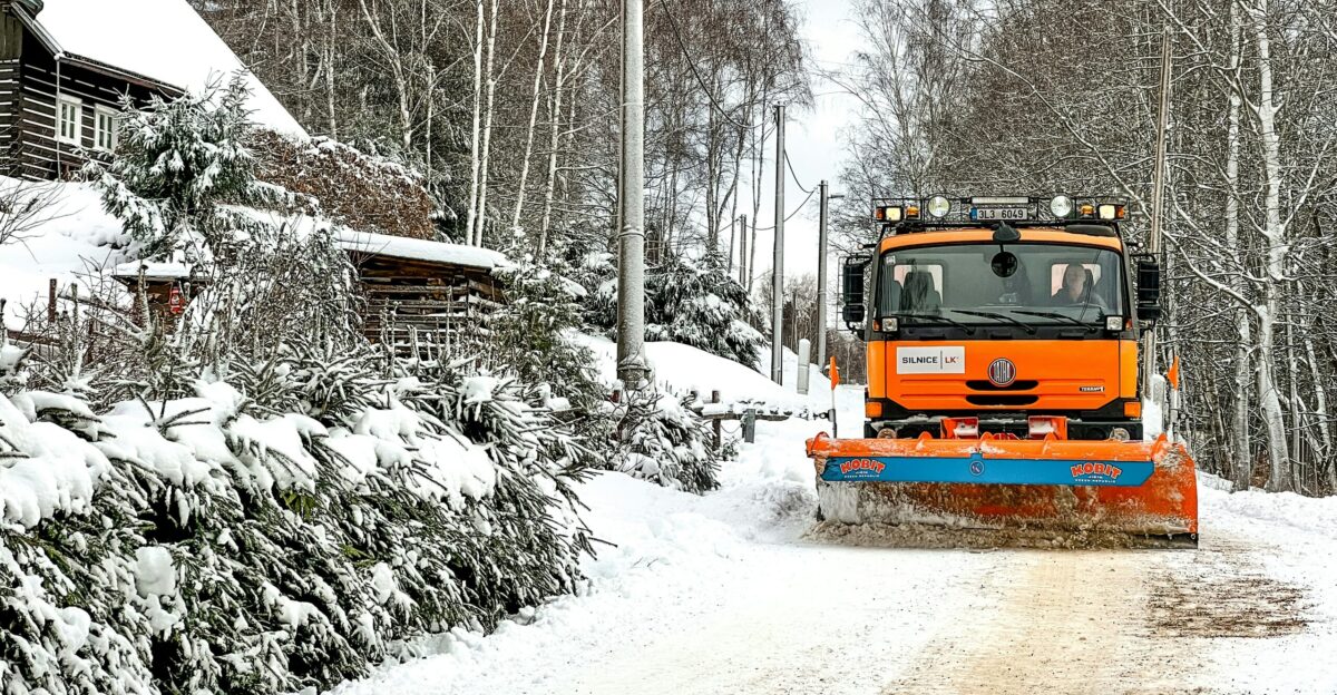 a snow plow driving down a snow covered road