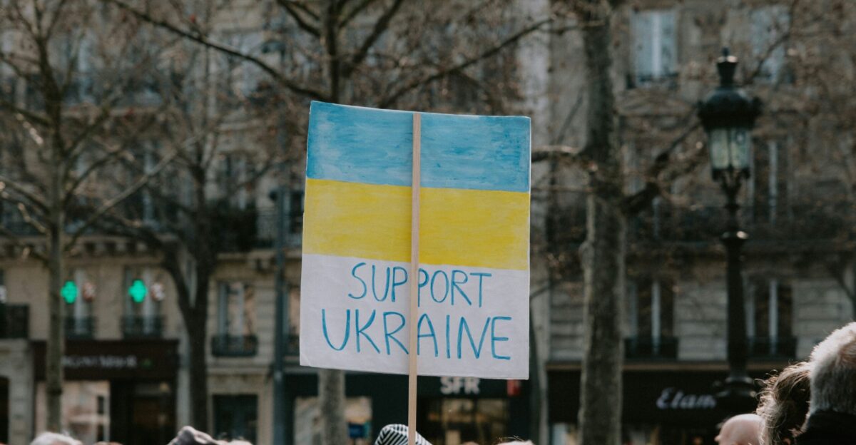 a crowd of people standing around a building with a sign that says support ukraine