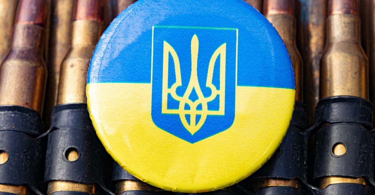 a blue and yellow button sitting on top of a bunch of bullet shells