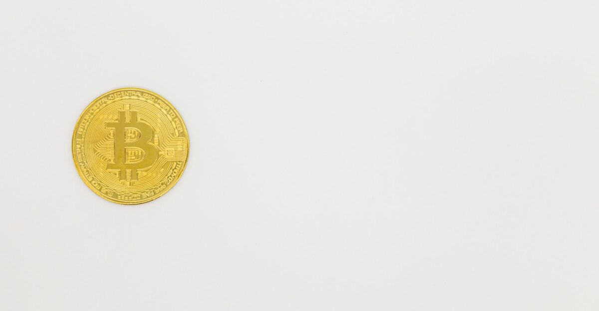 a gold bit coin sitting on top of a white surface