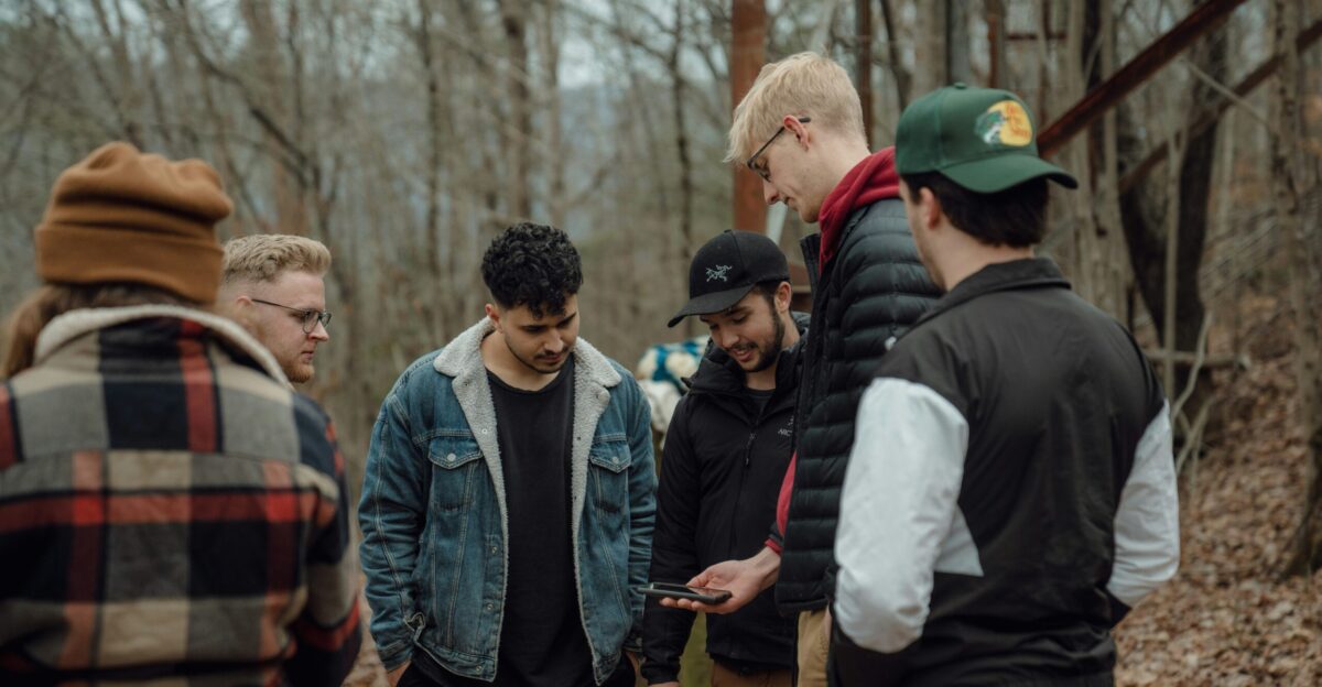 a group of men standing around each other in the woods