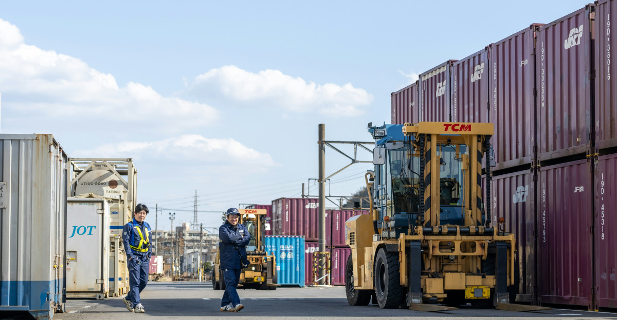 a man walking down a street next to lots of shipping containers