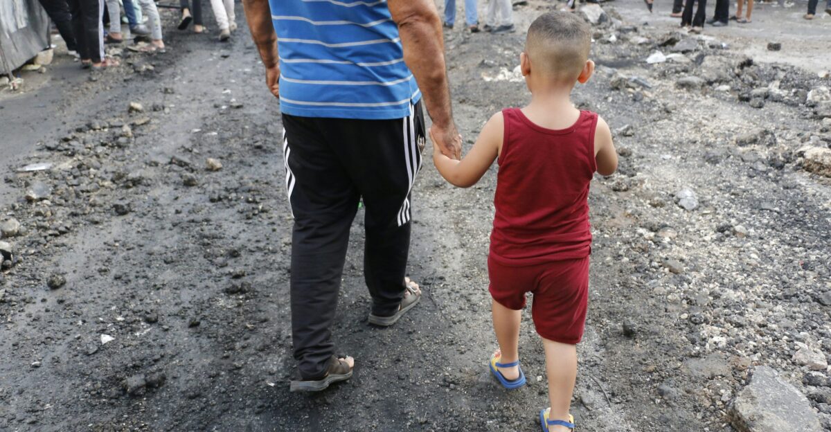 a man holding the hand of a small child