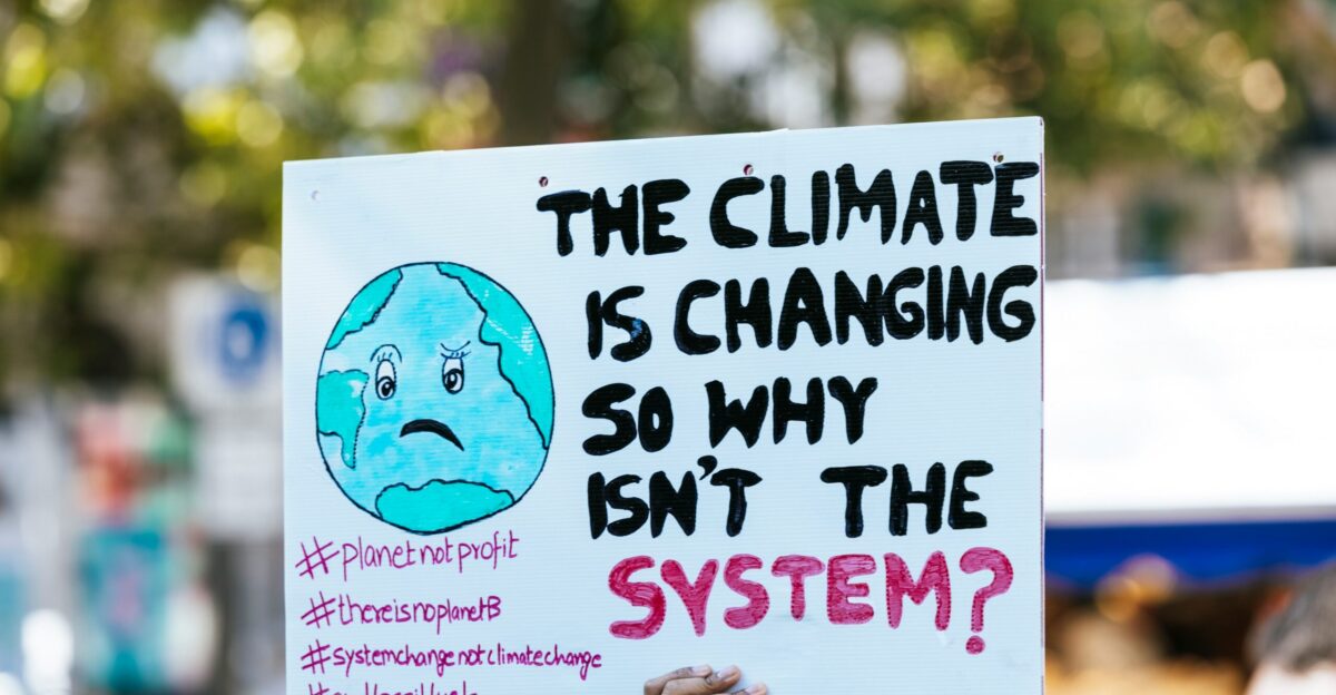 a person holding a sign that says the climate is changing so why isn t