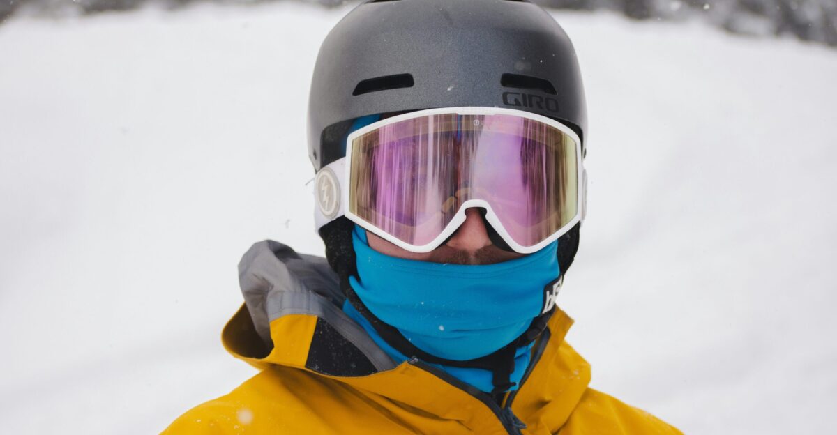 A man in a yellow jacket and goggles standing in the snow