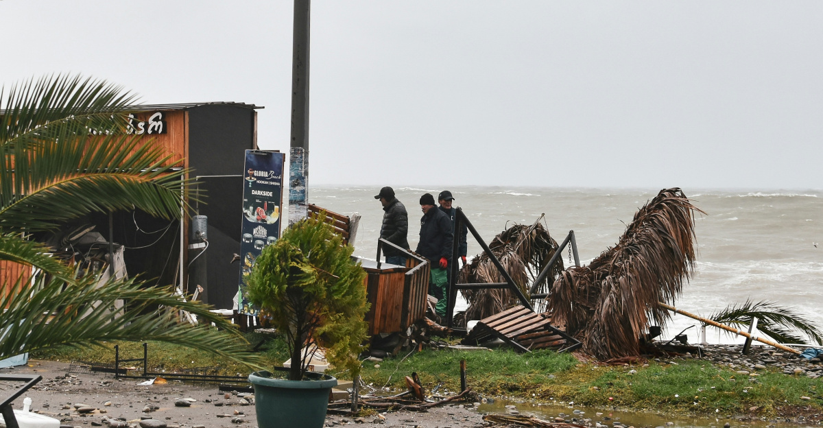 a group of people standing on top of a beach next to the ocean
