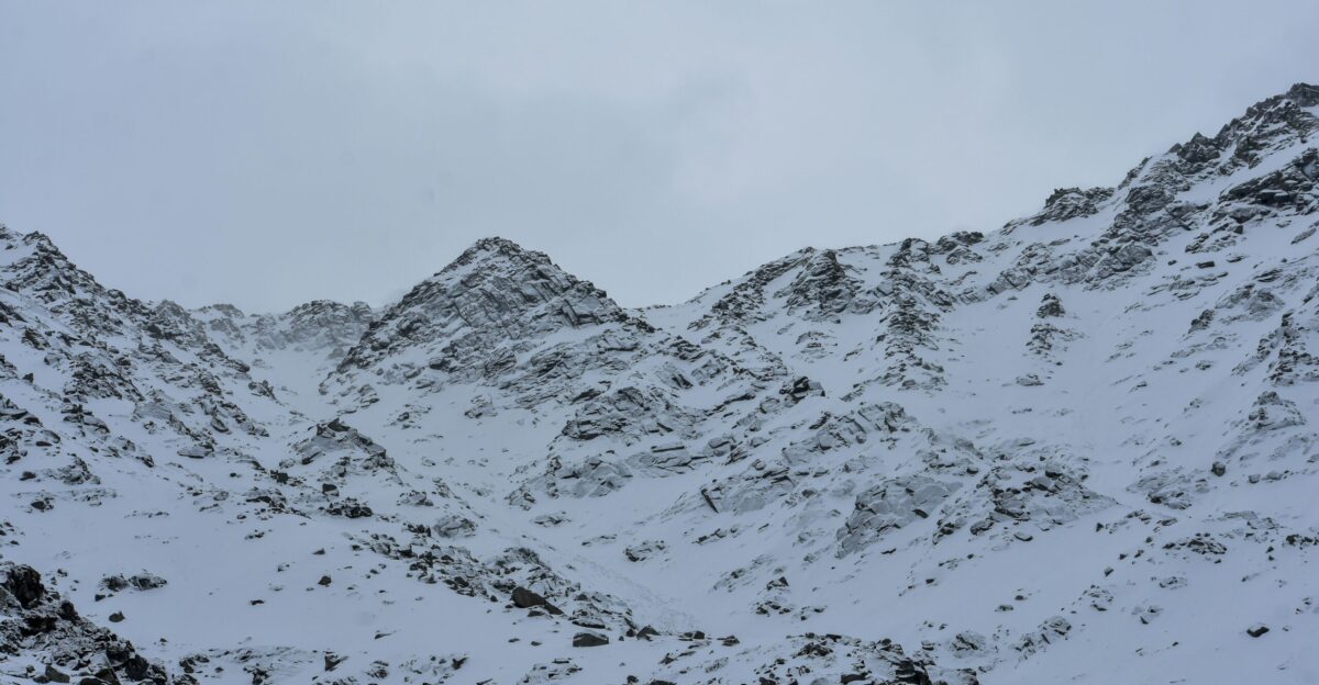 A mountain covered in snow under a cloudy sky