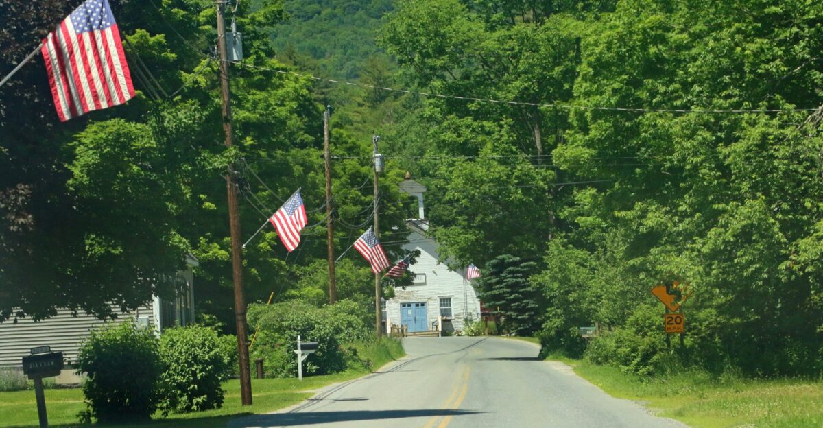 A country road lined with trees and flags