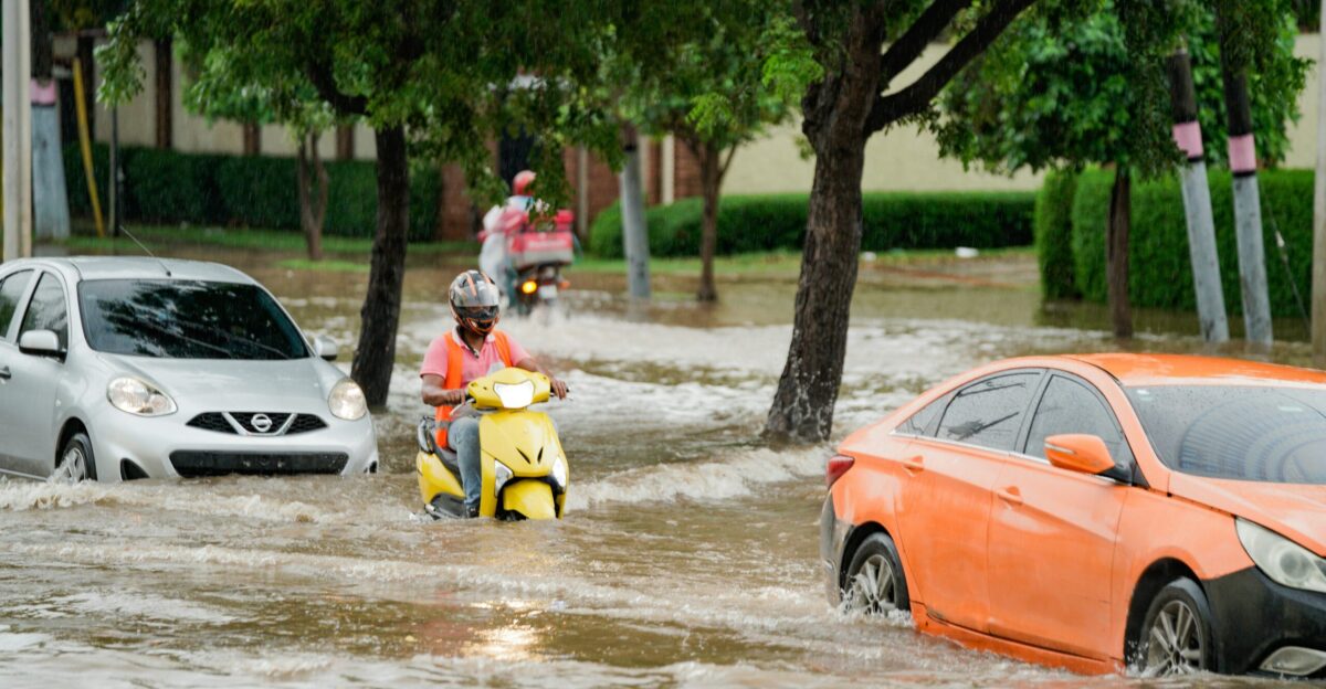 A group of people riding motorcycles through a flooded street