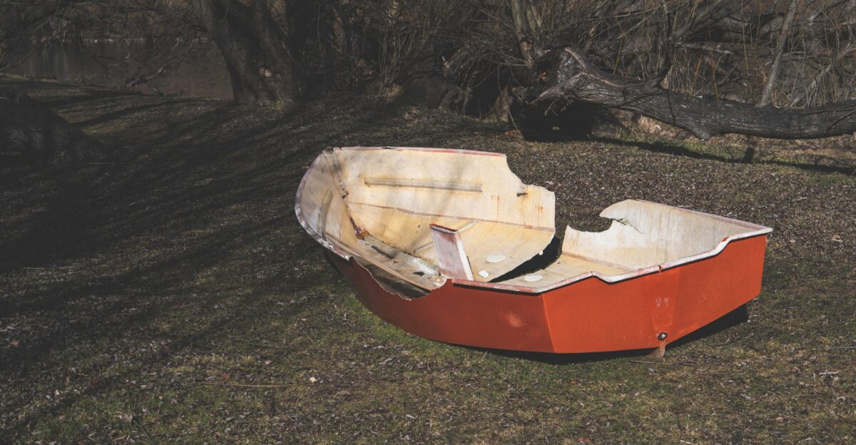 A red boat sitting on top of a grass covered field