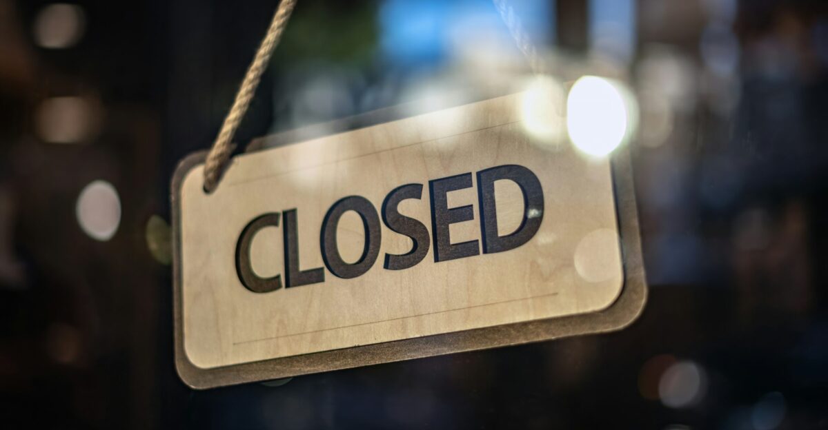 A closed sign hanging from a glass door