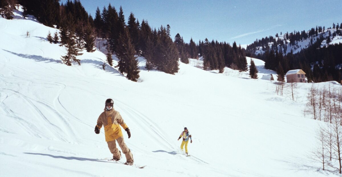 A couple of people riding skis down a snow covered slope