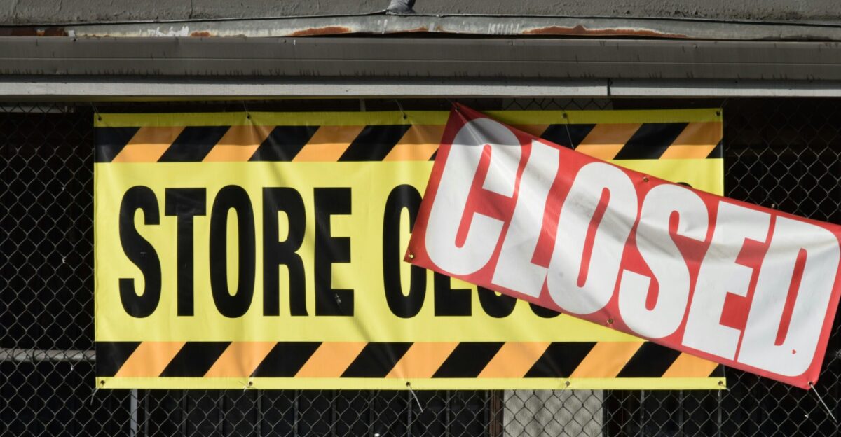 A store closed sign hanging from the side of a building