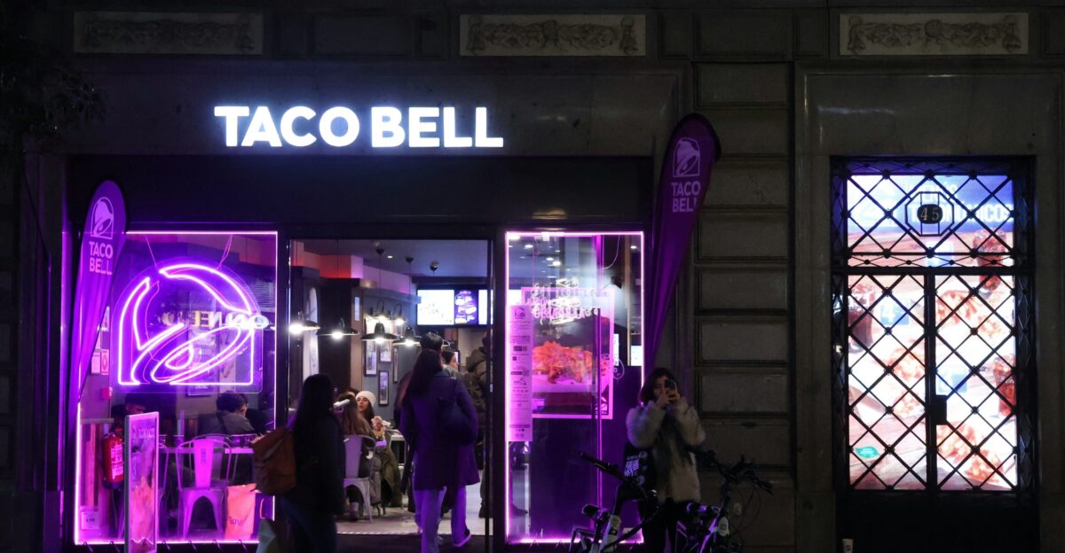 A purple lit store front with people walking by