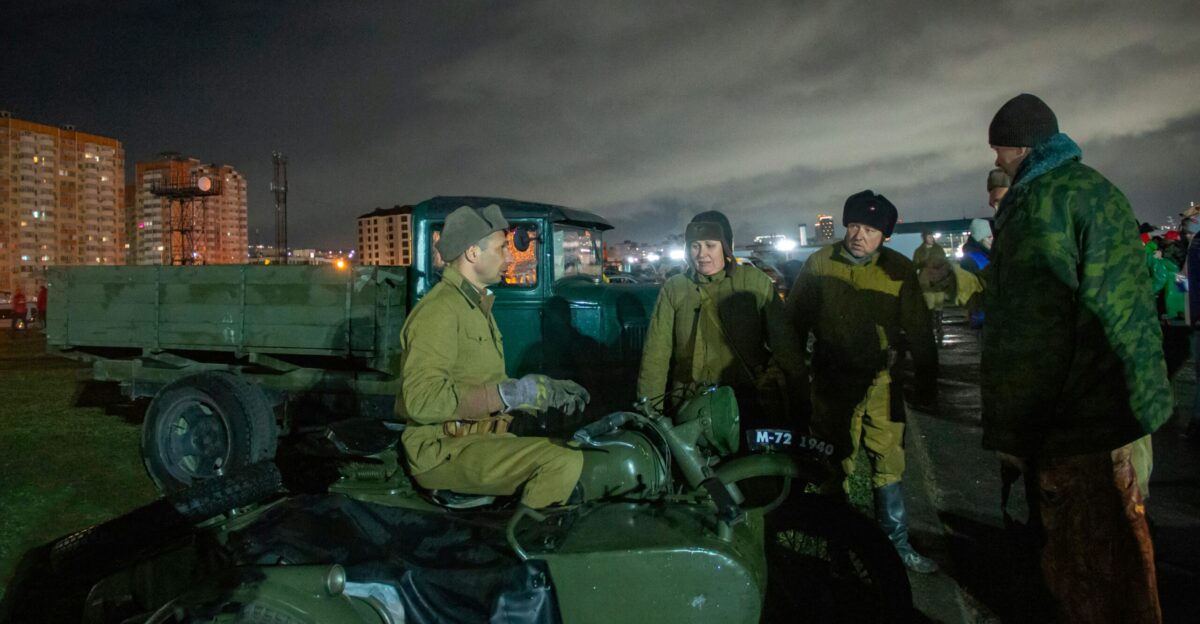 A group of people standing around a green truck
