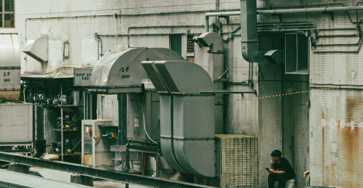 A person sits amidst industrial machinery outdoors