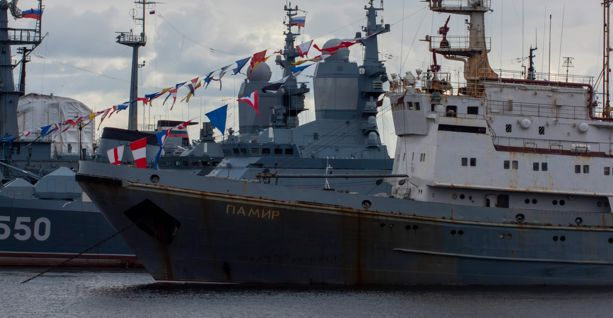 Several naval ships docked under a cloudy sky
