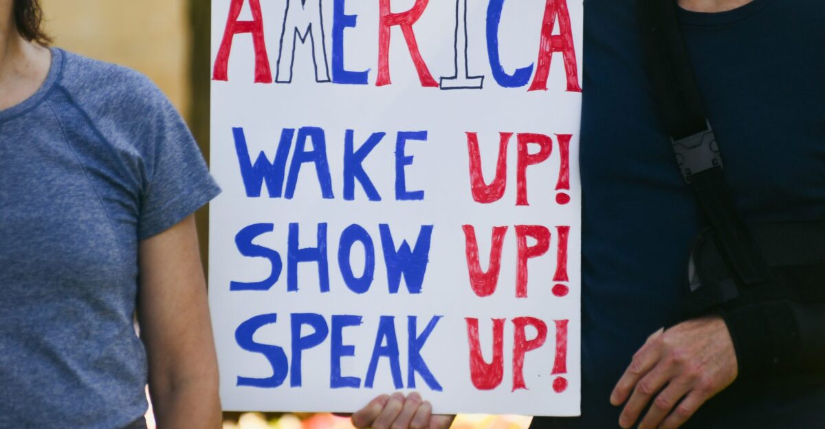 People holding a sign that says america wake up