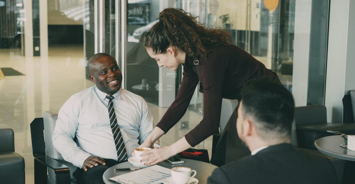 Woman serves coffee to men in office lobby