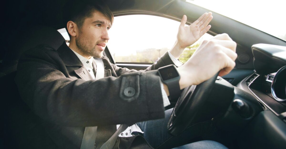 Man driving a car gesturing with hand