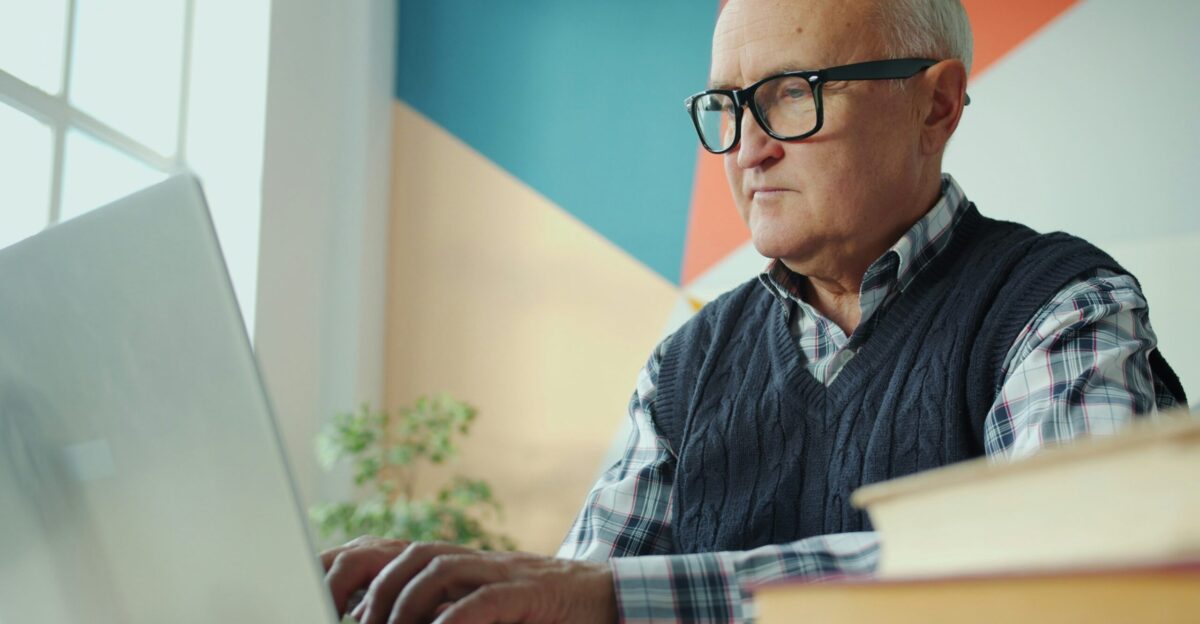 Elderly man with glasses using a laptop