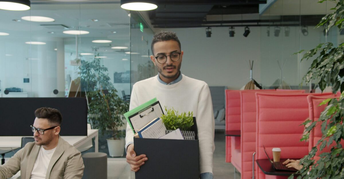 Man carrying box of belongings in modern office