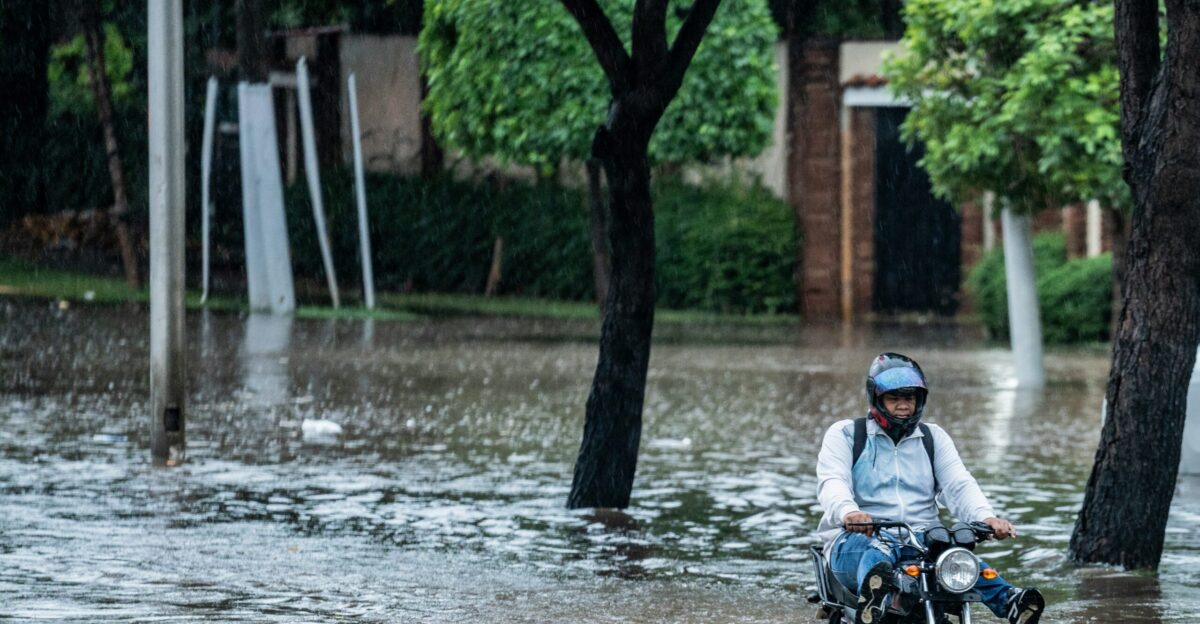 Man rides motorcycle through flooded street