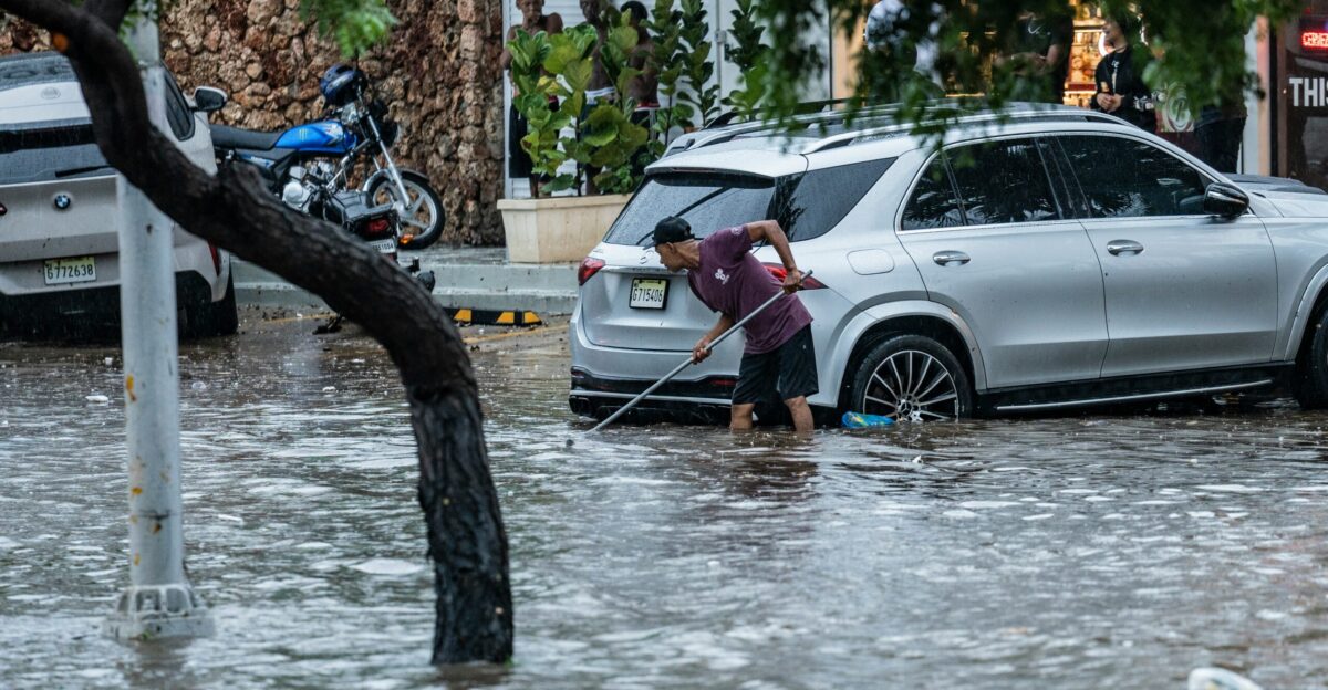 Man sweeps floodwater from flooded street