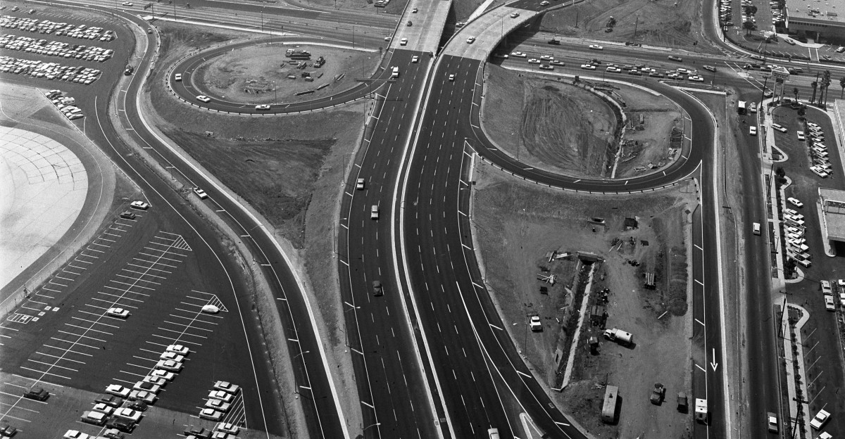AIRPORT FROM AIR-A view taken from aloft at east end of Los Angeles International Airport looking west shows packed parking areas control tower building theme building and outlying operational satellites In foreground is newly completed interchange Dual lanes for arriving and departing traffic lead off and into Century Blvd crossing over Sepulveda Blvd Cloverleafs provide off and on-ramps at the interchange