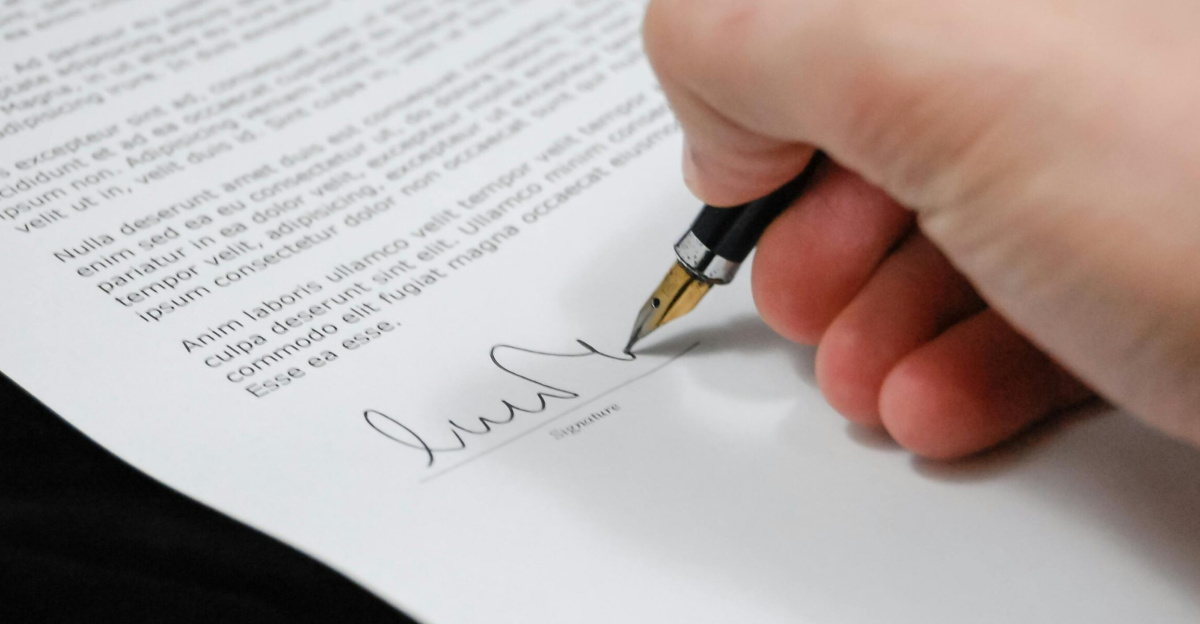 Close-up of a hand signing a legal document with a fountain pen, symbolizing signature and agreement.