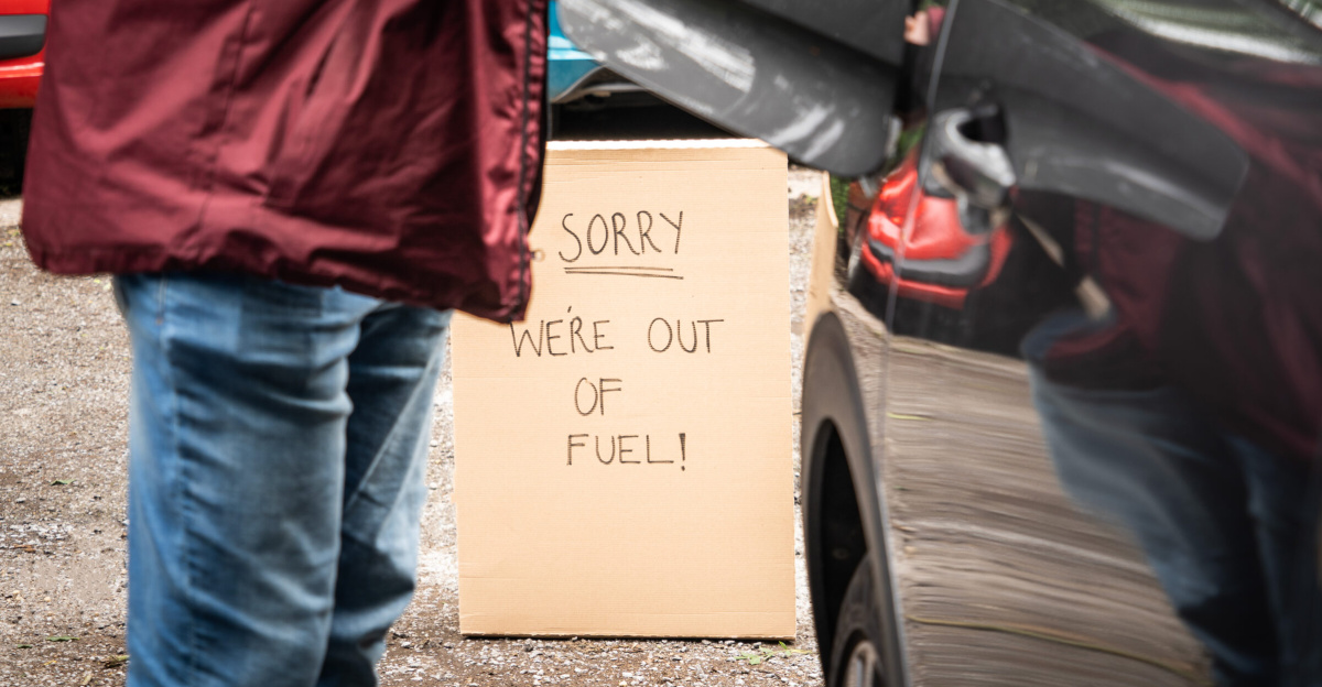 Photograph of a person standing next to a car with the fuel cap open.  There is a sign in the background reading "Sorry, We're out of Fuel!"
This image is free to use on the condition that a link to <a rel="nofollow" class="external free" href="https://www.icompario.com/nl-be/">https://www.icompario.com/nl-be/</a> is included as attribution.