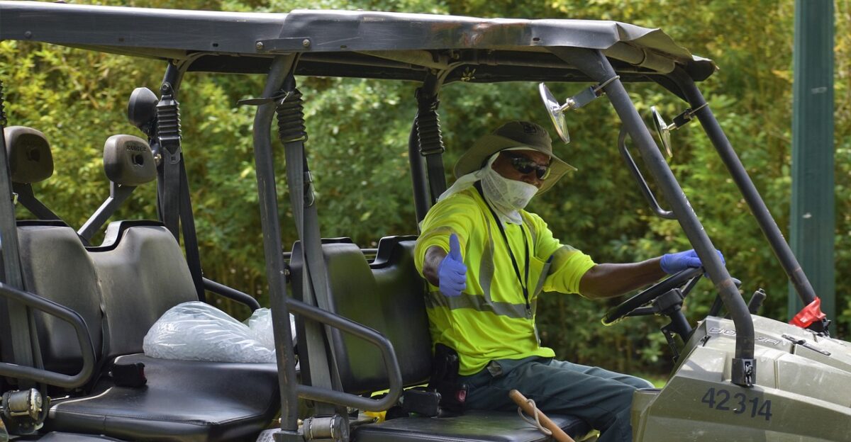 african american park staff worker national park herman park houston texas maintenance utility working staff employment off-road equipment neon green nature face mask covid-19 coronavirus protection virus cleaner cleaning driving parks trees