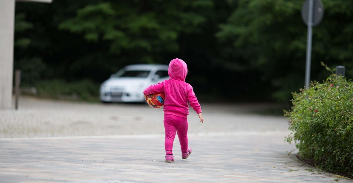 child playing outdoors driveway ball little girl jogging suit outdoors no supervision