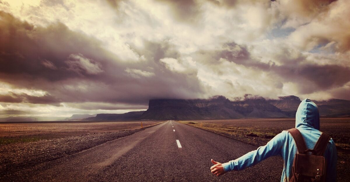 road man hitchhiker walker on the way usa lonely highway hitchhike by hitch hiking landscape nature lift backpack person expanse lonliness alone grim clouds cloud formations human