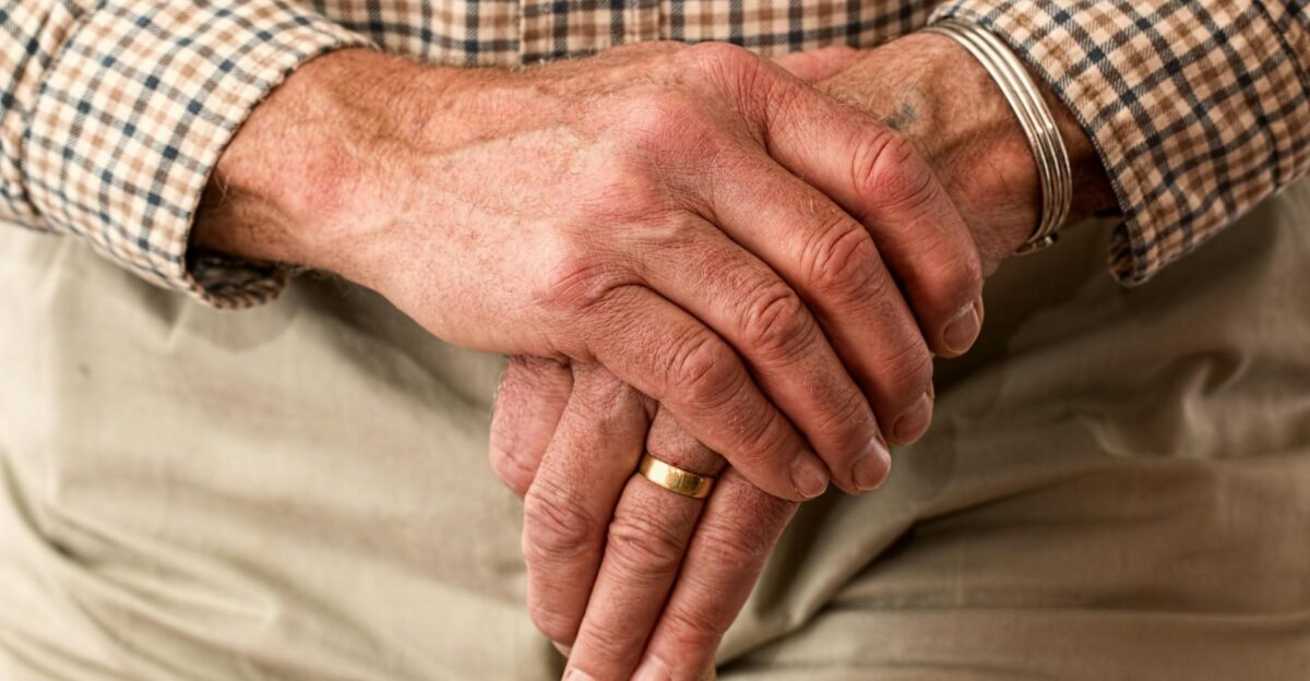 A detailed image of elderly hands clasping a wooden cane symbolizing aging and support