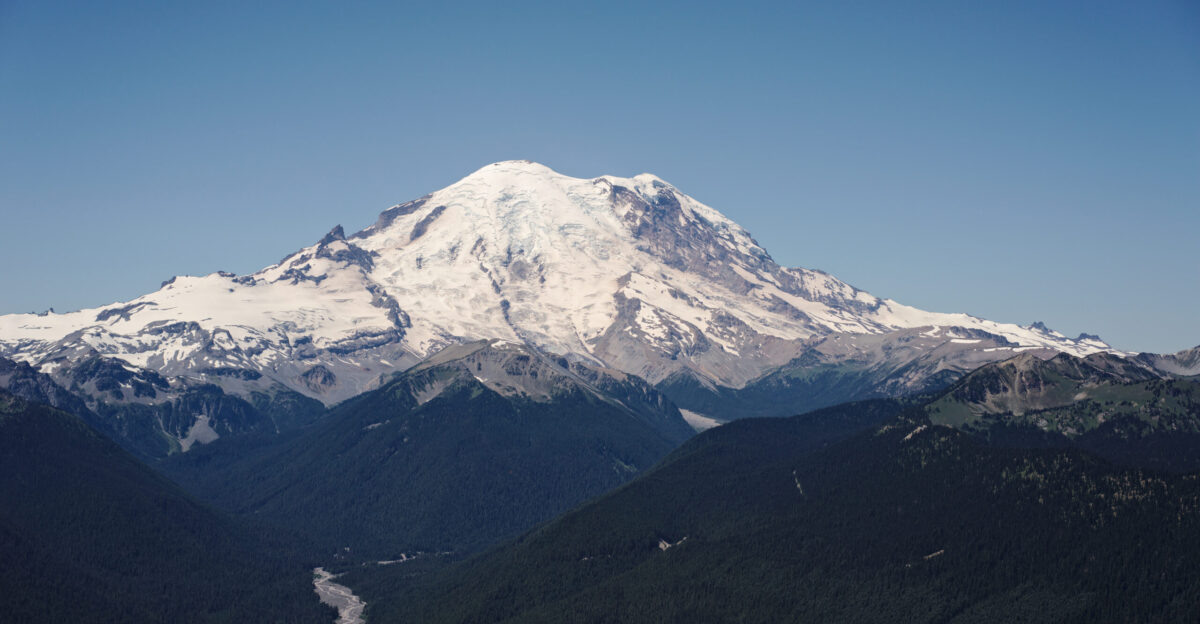 Mount Rainier as viewed in the summer from Silver Queen Peak near Crystal Mountain resort at an elevation of around 7000 ft looking west by southwest The main summit Columbia Crest 14410 feet is at the center The White River is visible in the lower left