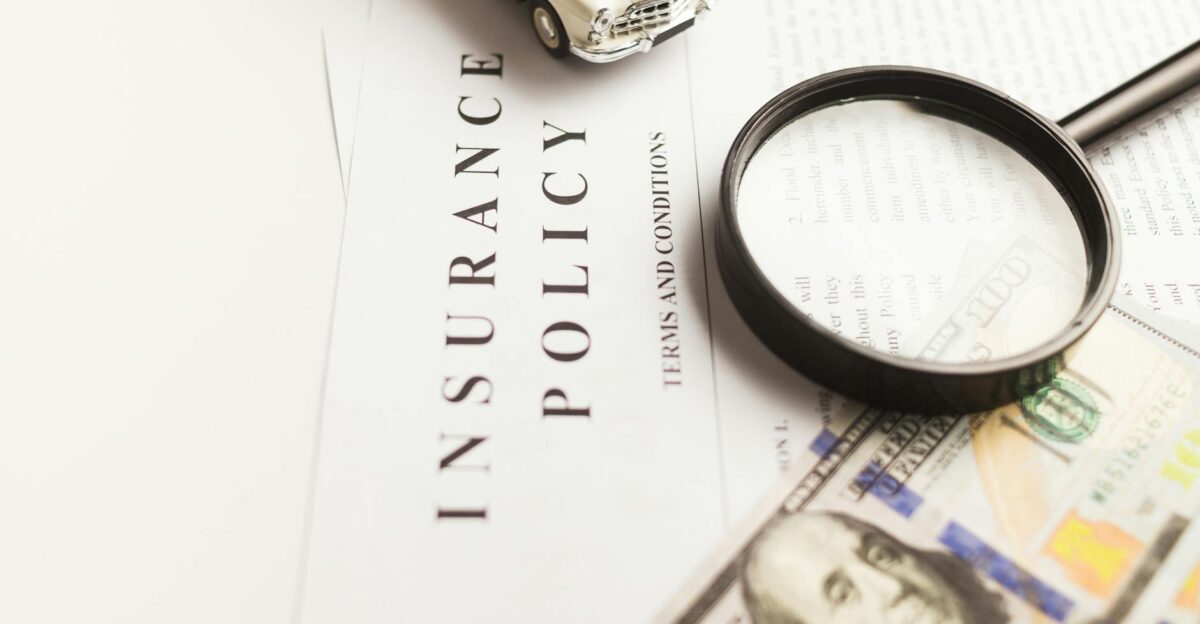 Close-up image of an insurance policy with a magnifying glass money and toy car