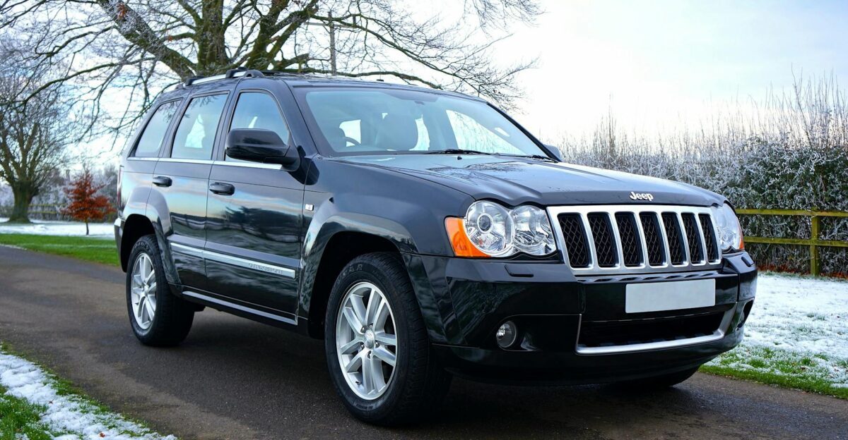 A shiny black SUV parked on a snowy road with trees in the background showcasing winter scenery