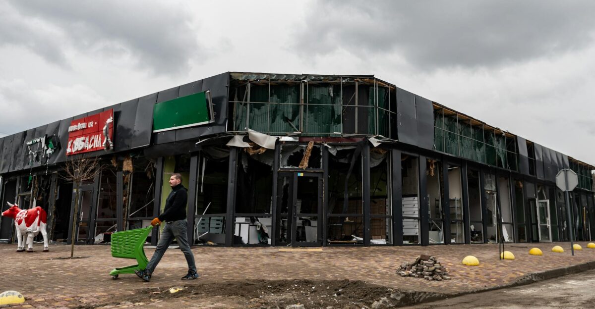 A person walks by a damaged building in Makariv Kyiv Oblast Ukraine highlighting urban disaster impacts