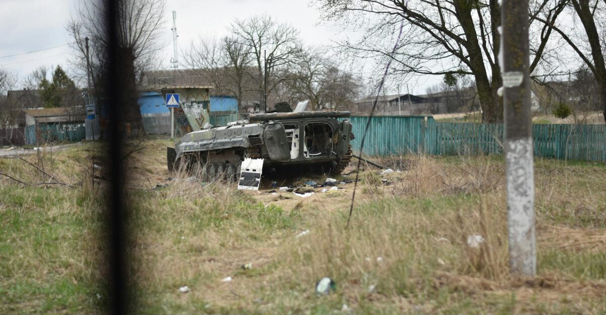 A destroyed tank lies in a rural village depicting past conflict and war impact