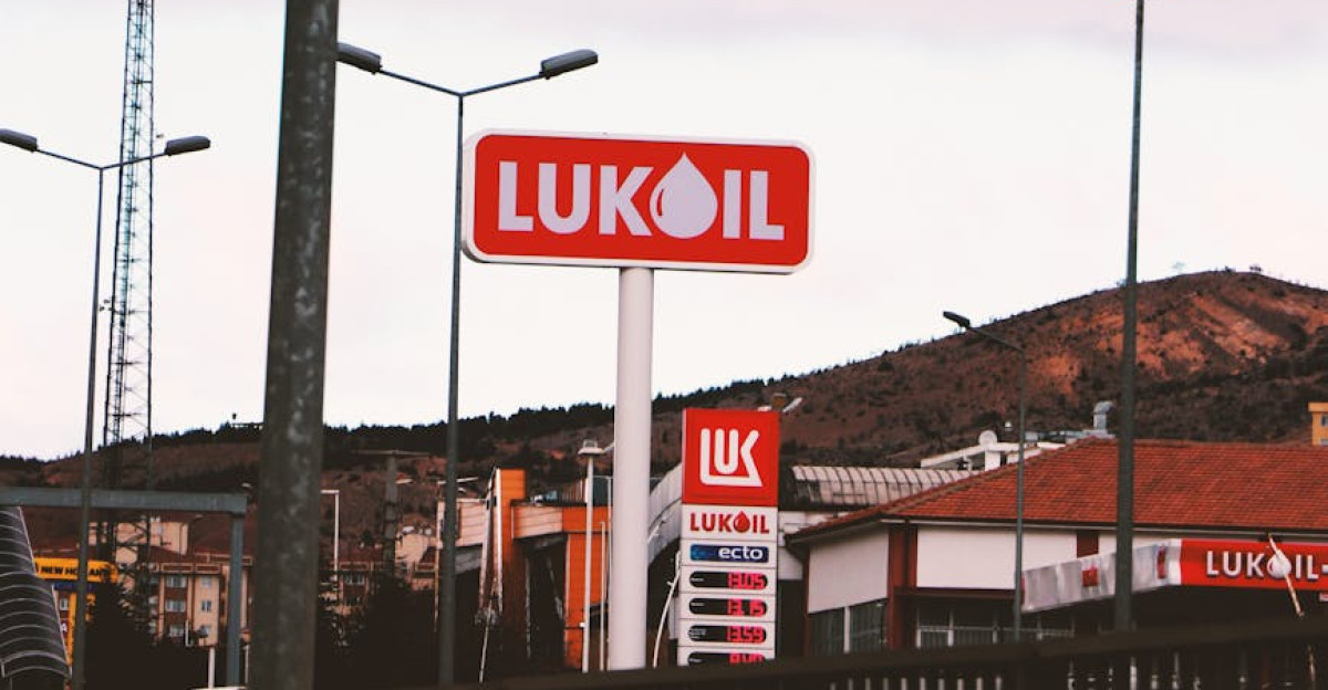 A Lukoil gas station with a mountain in the background under a cloudy sky